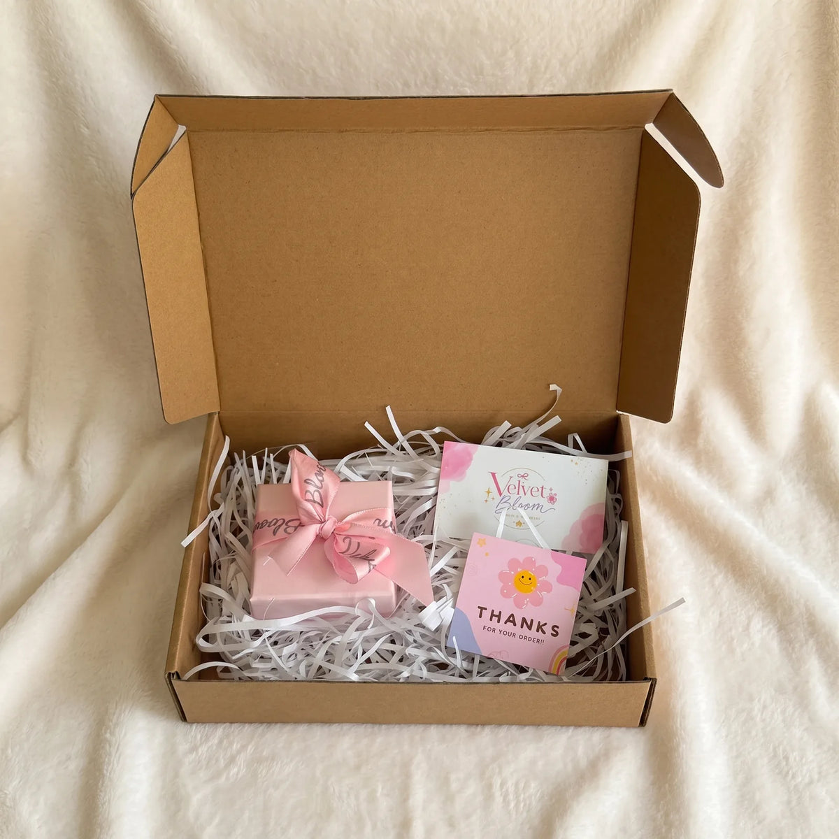 Pedido de Velvet Bloom abierto: caja de envío, cajita rosa y tarjeta de agradecimiento.