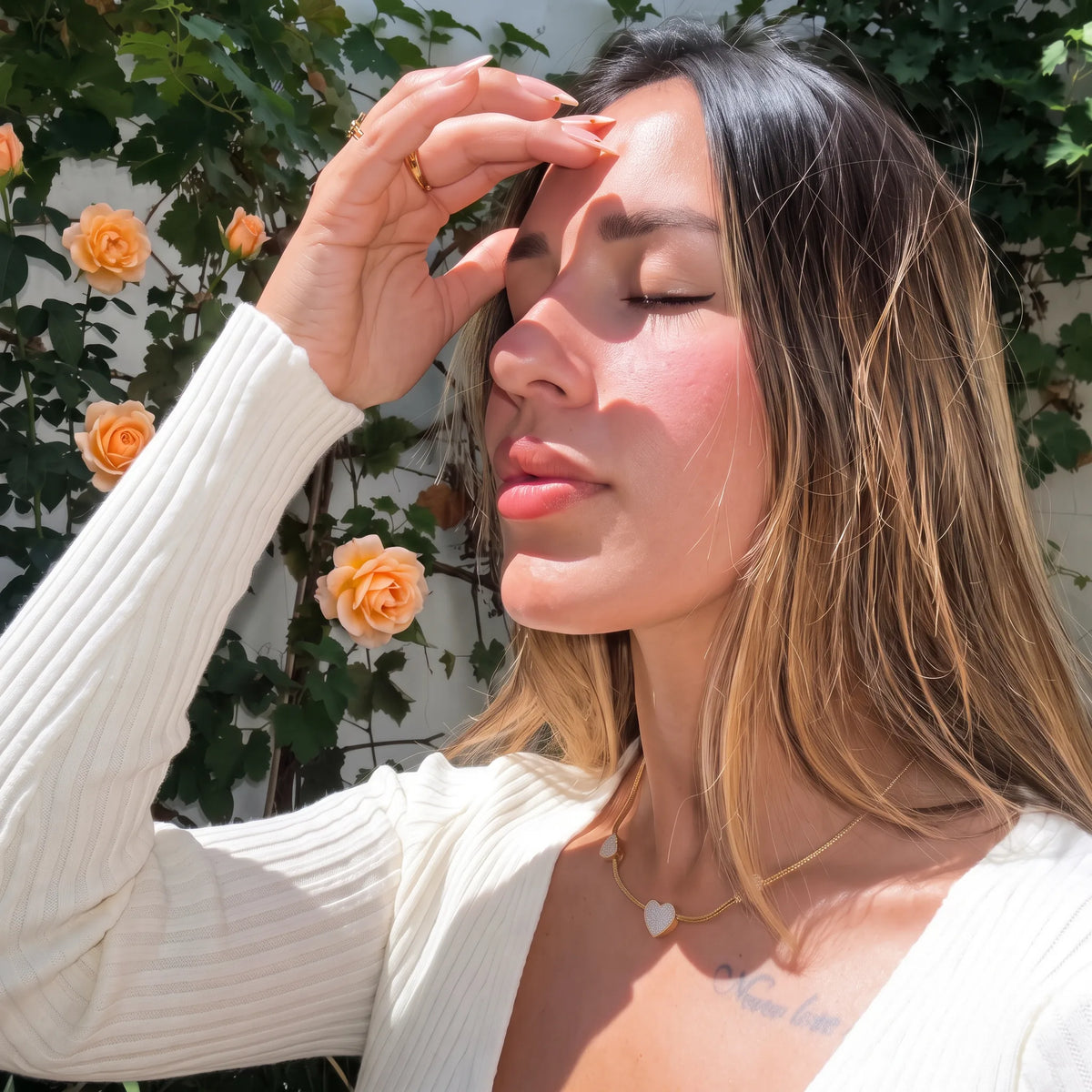 Vanessa disfrutando el sol junto a rosas, con collar de corazones Velvet Bloom